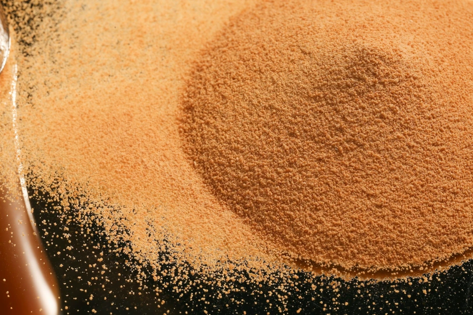 a pile of sand next to a bottle of brown liquid